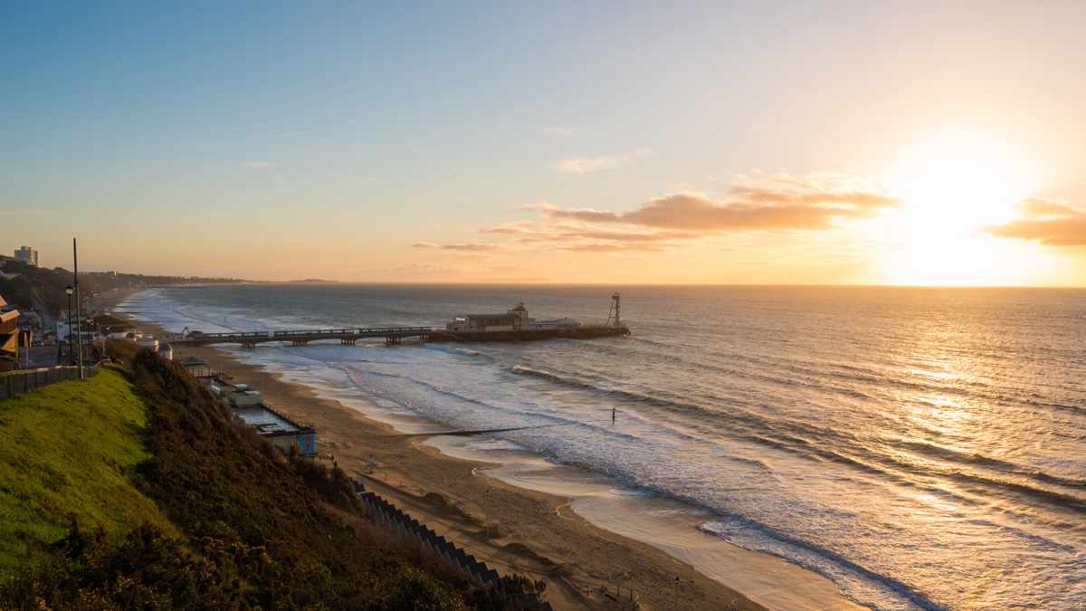 Bournemouth Pier and the long sandy beach curving away below the clifftop at sunrise
