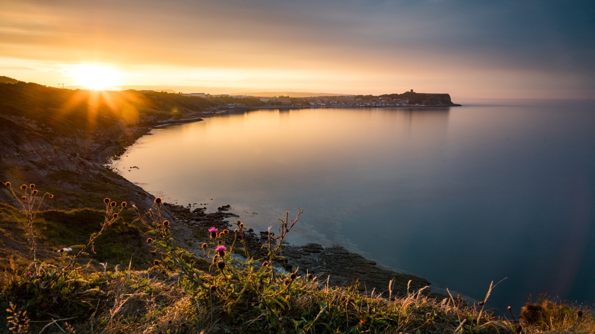 Sunset over Scarborough bay, the castle headland on the horizon, North Yorkshire