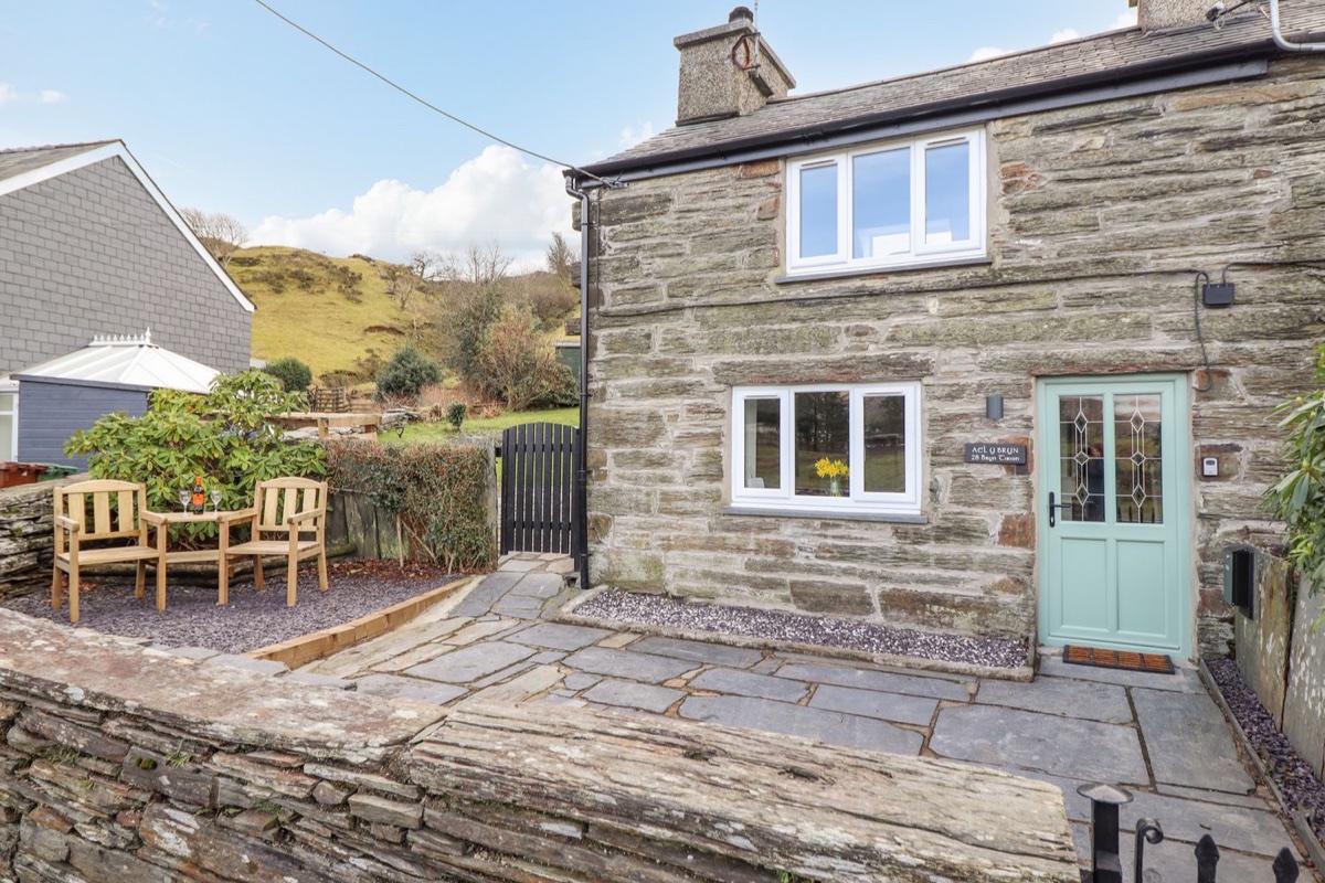 Ael Y Bryn cottage exterior with outdoor seating and hillside context