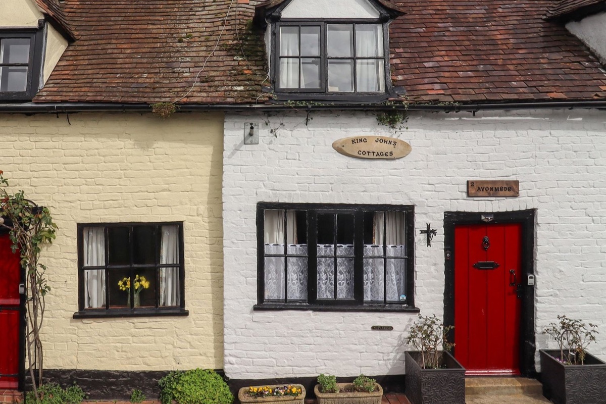 Avonmede cottage exterior with red doors, dark windows and potted plants