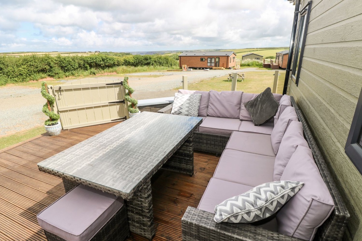 Beechwood Lodge decking with a rattan dining set and open countryside views in Little Haven