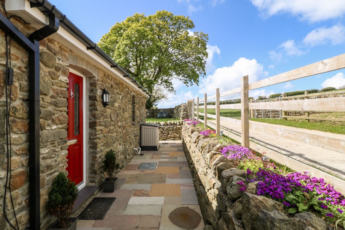 Beudy Tyddyn stone cottage with red door and flowered wall