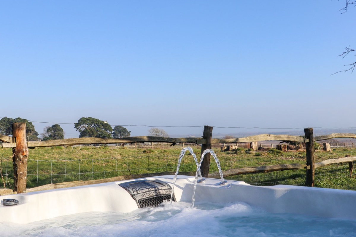 Hot tub with water jets overlooking open countryside at Birch Cottage near Rye