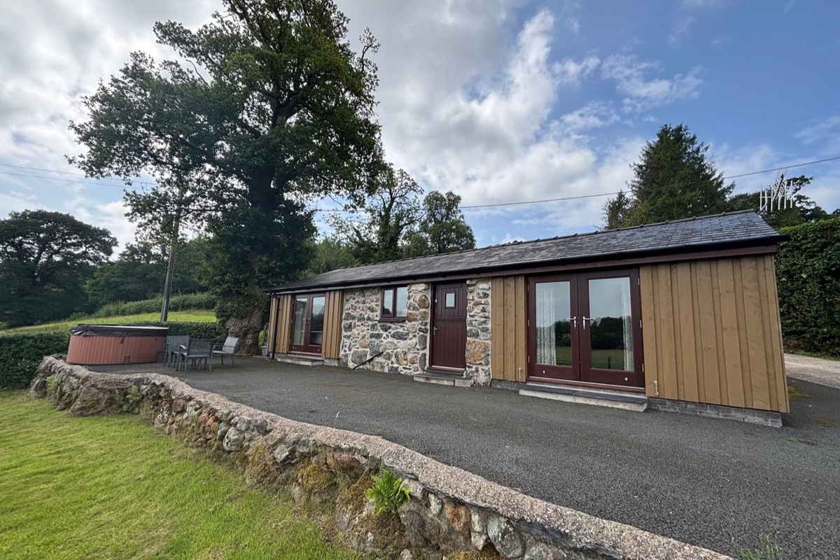 Bothi exterior with stone wall, lawn and hot tub