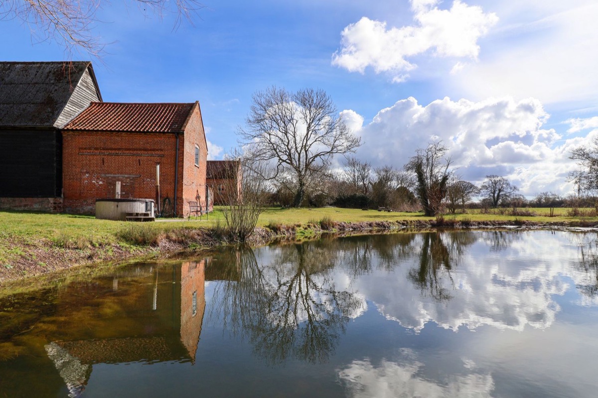 Brook Farm reflected in the pond with its brick exterior