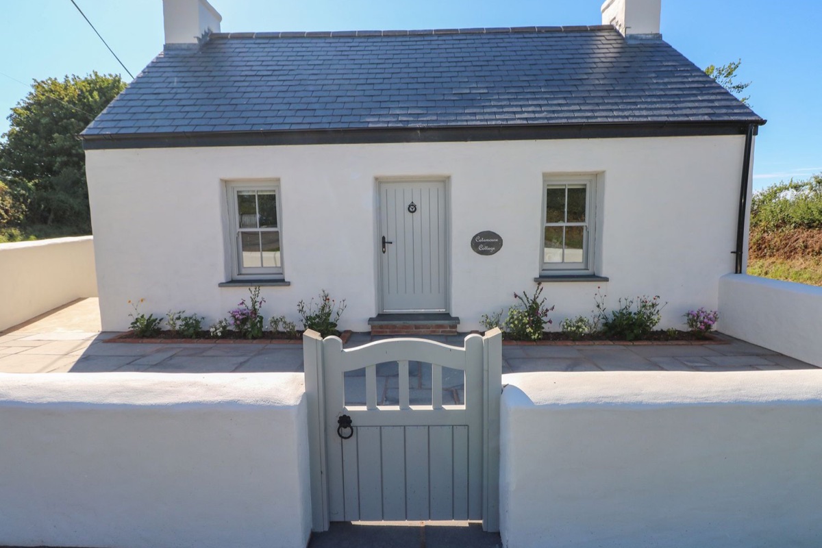 Whitewashed cottage with a slate roof and painted gate at Catamouse in Milford Haven