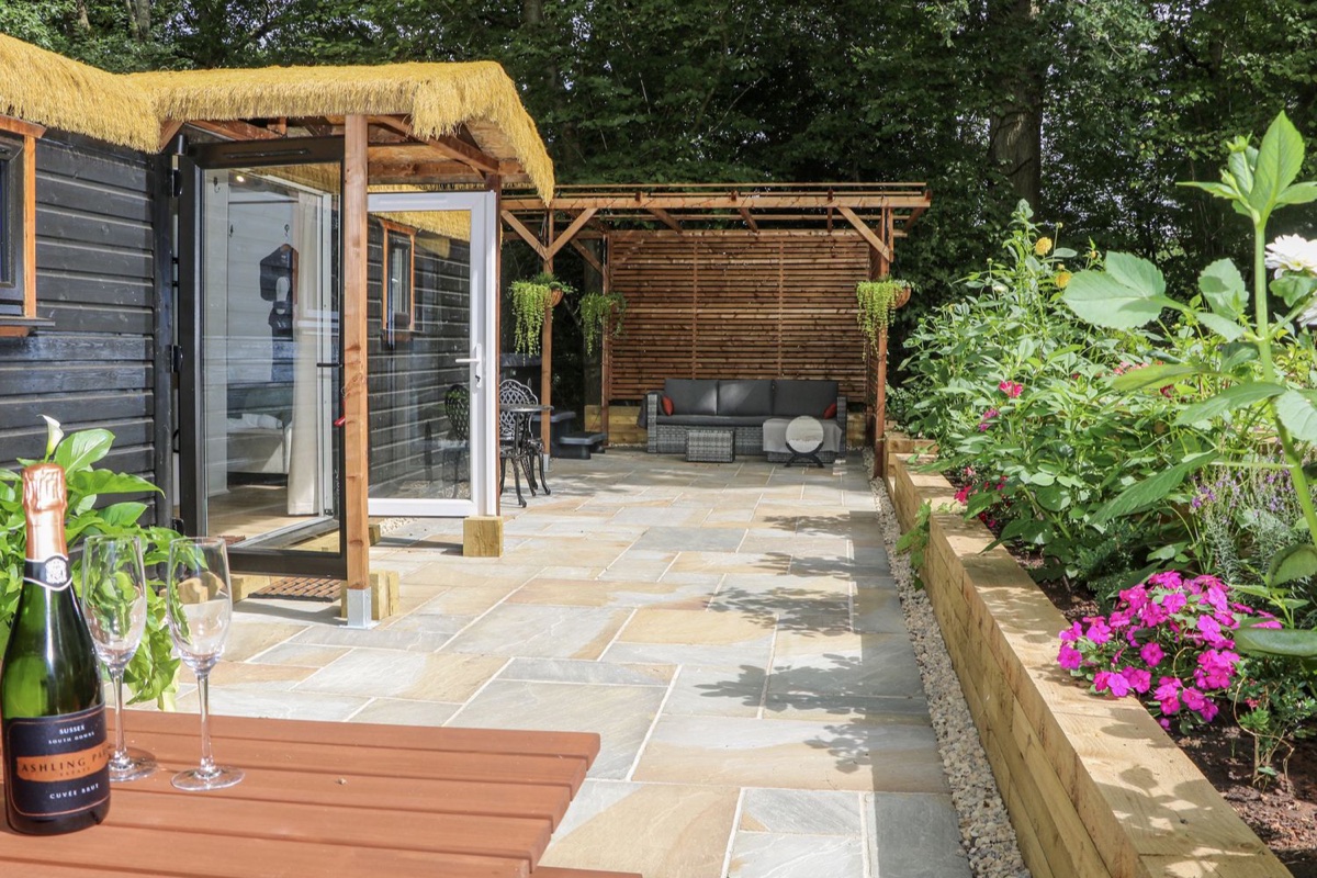 Charltons Hollow Cabin with a thatched porch and a pergola seating patio near Bolney