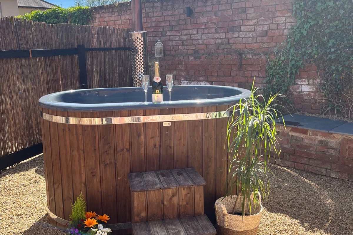 Coach Lodge wood-fired hot tub in a walled gravel courtyard