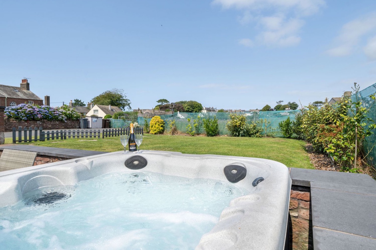 Bubbling hot tub with champagne glasses and garden at Coney Garth Retreat