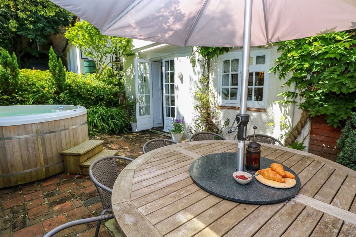 Coppice Hill House patio with hot tub, garden table and white cottage exterior