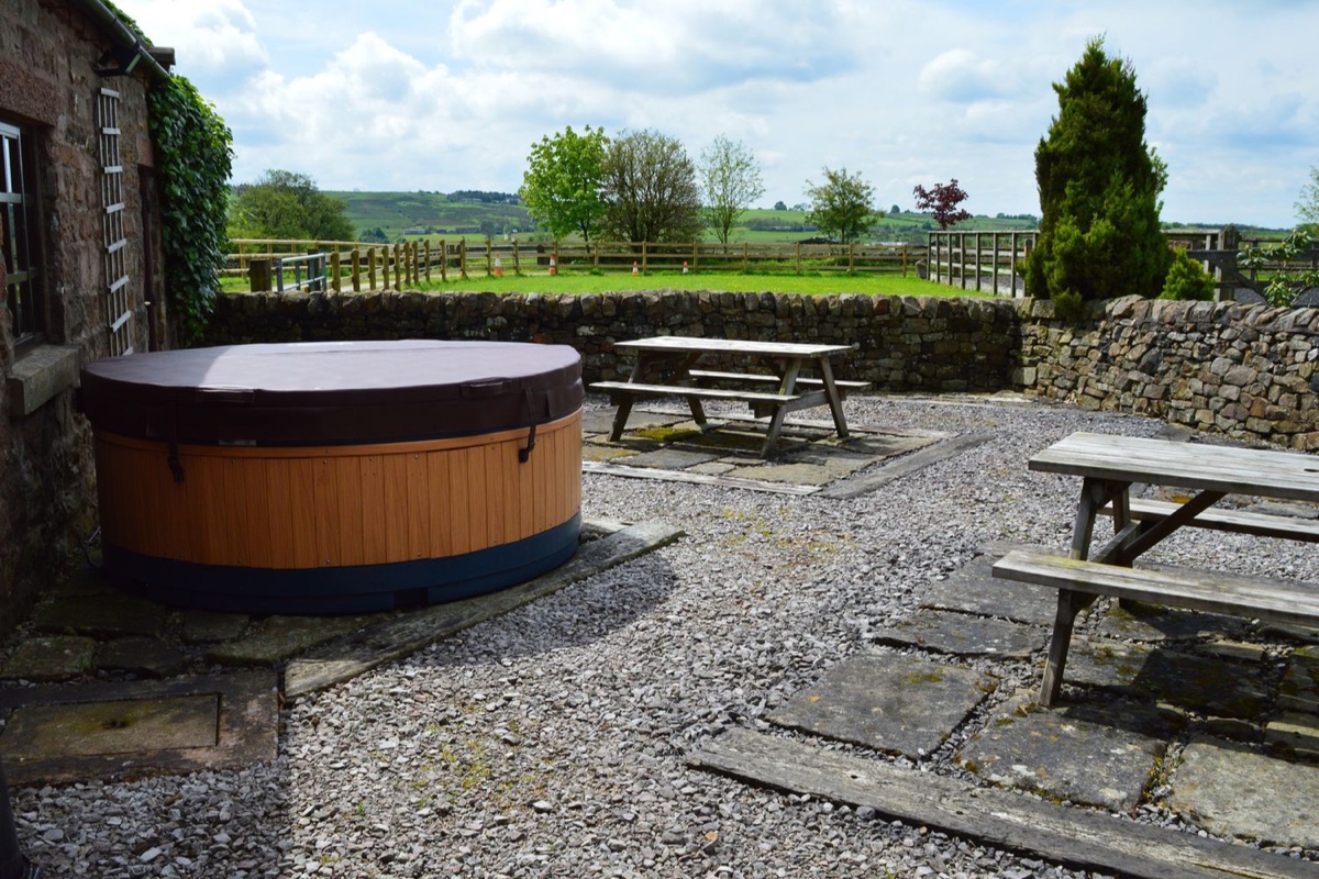 Wood-clad hot tub on the yard with a dry-stone wall and countryside at Curlew Barn
