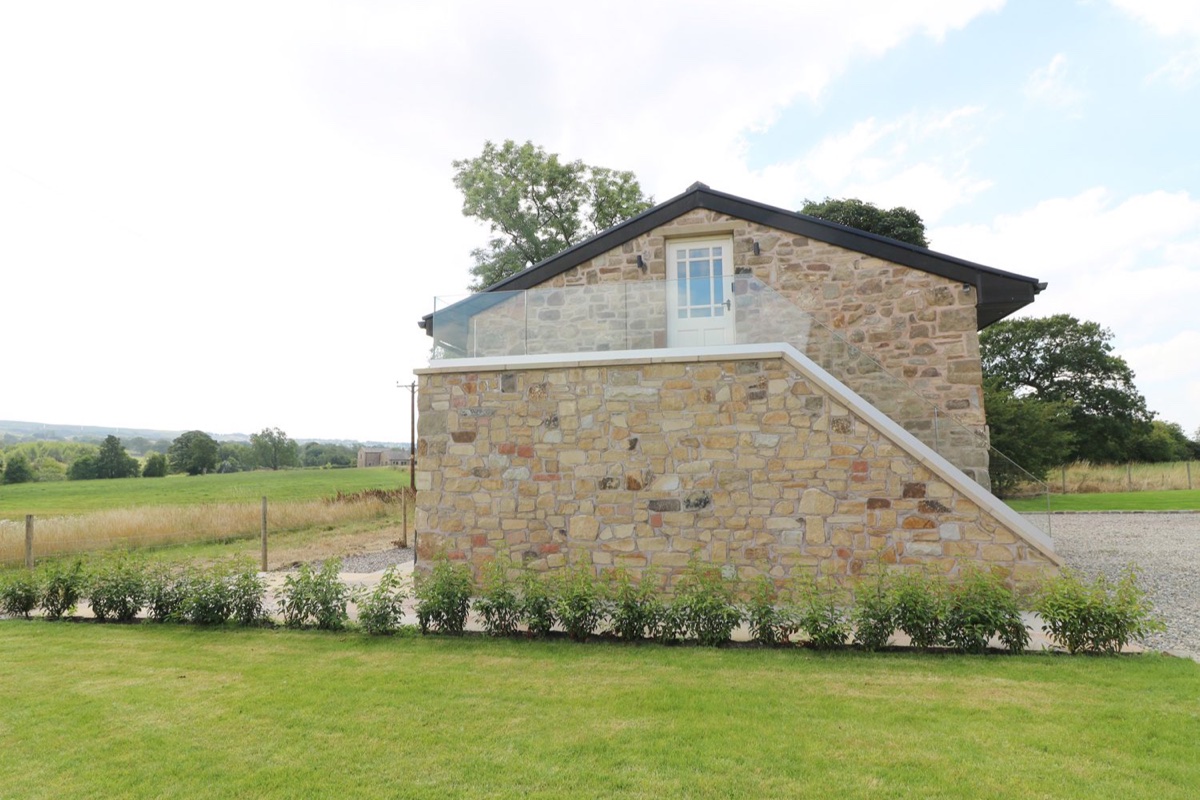 Deer Lodge stone exterior with balcony and open fields