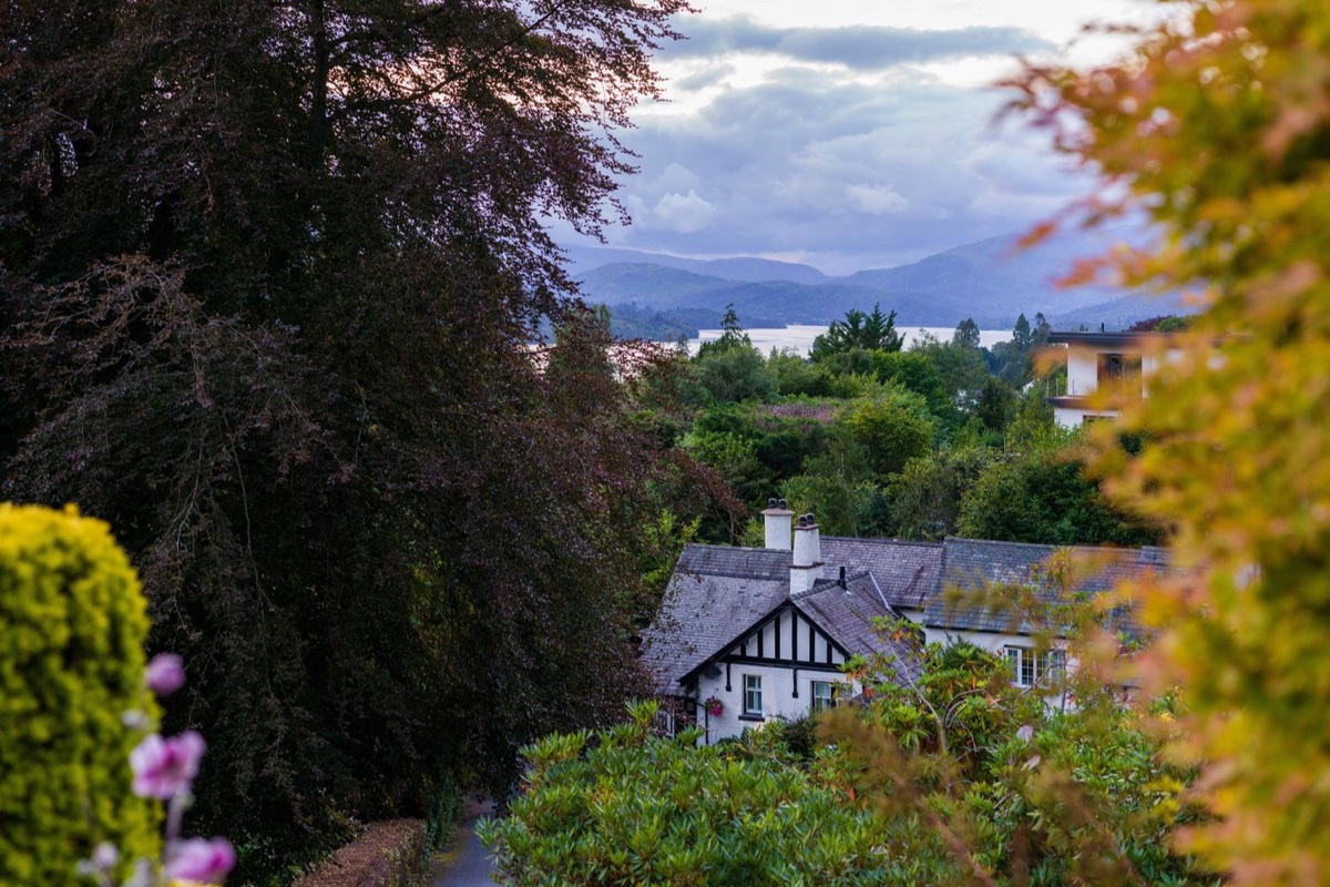 Fellside Lodge through autumn foliage with Windermere and fells beyond