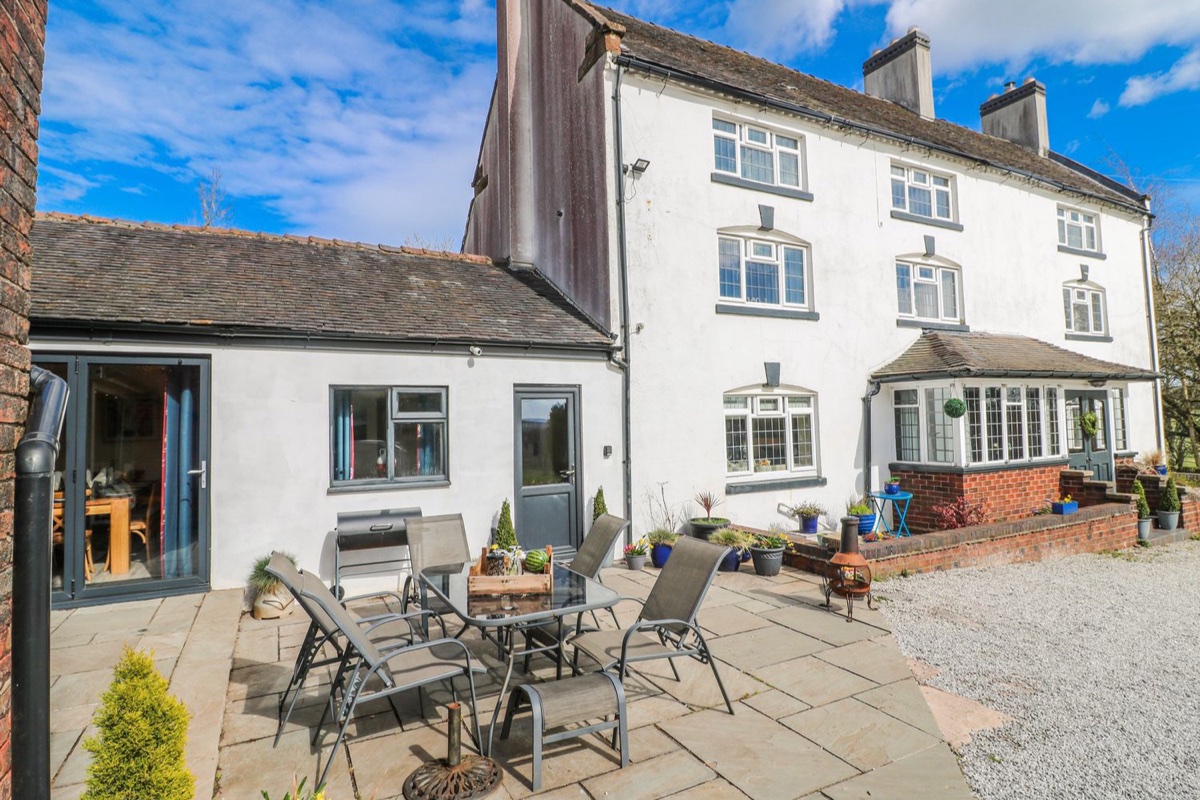 Large white three-storey farmhouse with a flagstone patio at Fields Farm near Cheadle