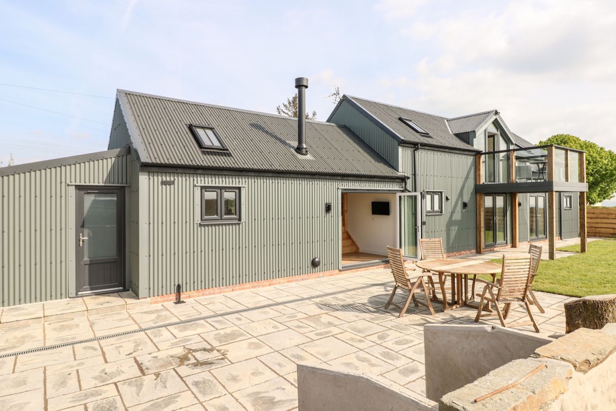 Green timber-clad barn conversion at Glowty Brynbedw with glass balcony and patio