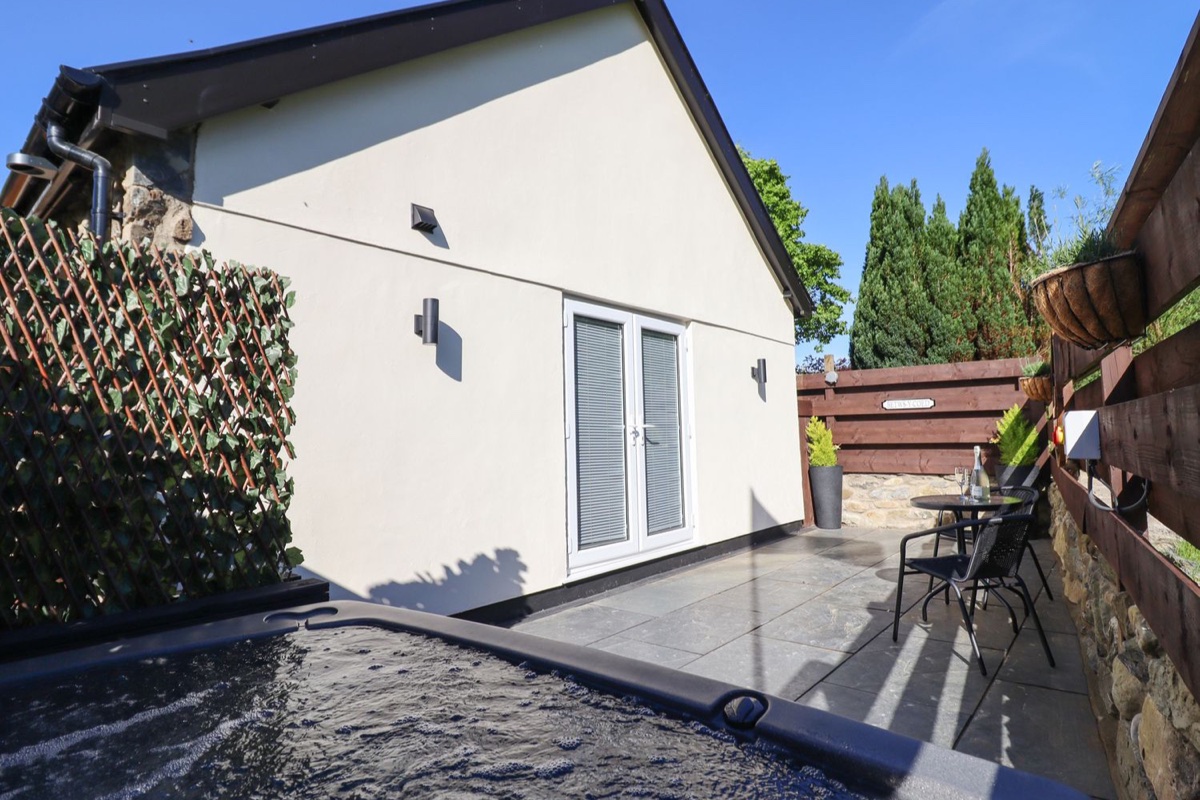 Glyndwr exterior patio with hot tub beside the cottage