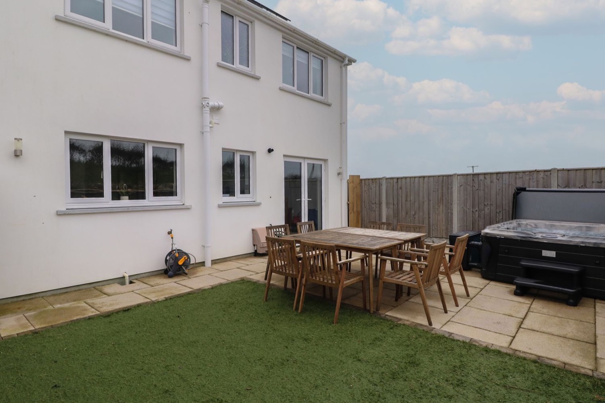 Rear garden with lawn, dining table and hot tub at Golygfa Hafan