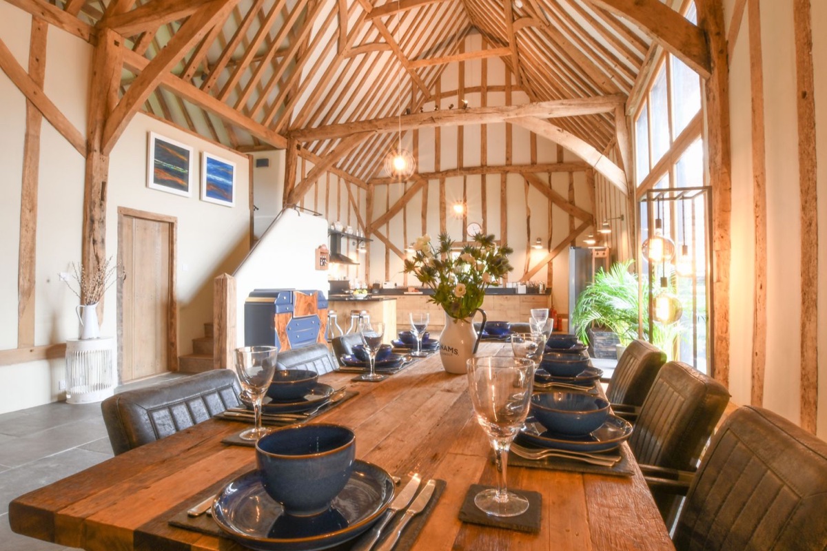 Beamed dining hall and kitchen under the vaulted roof at Halcyon Barn