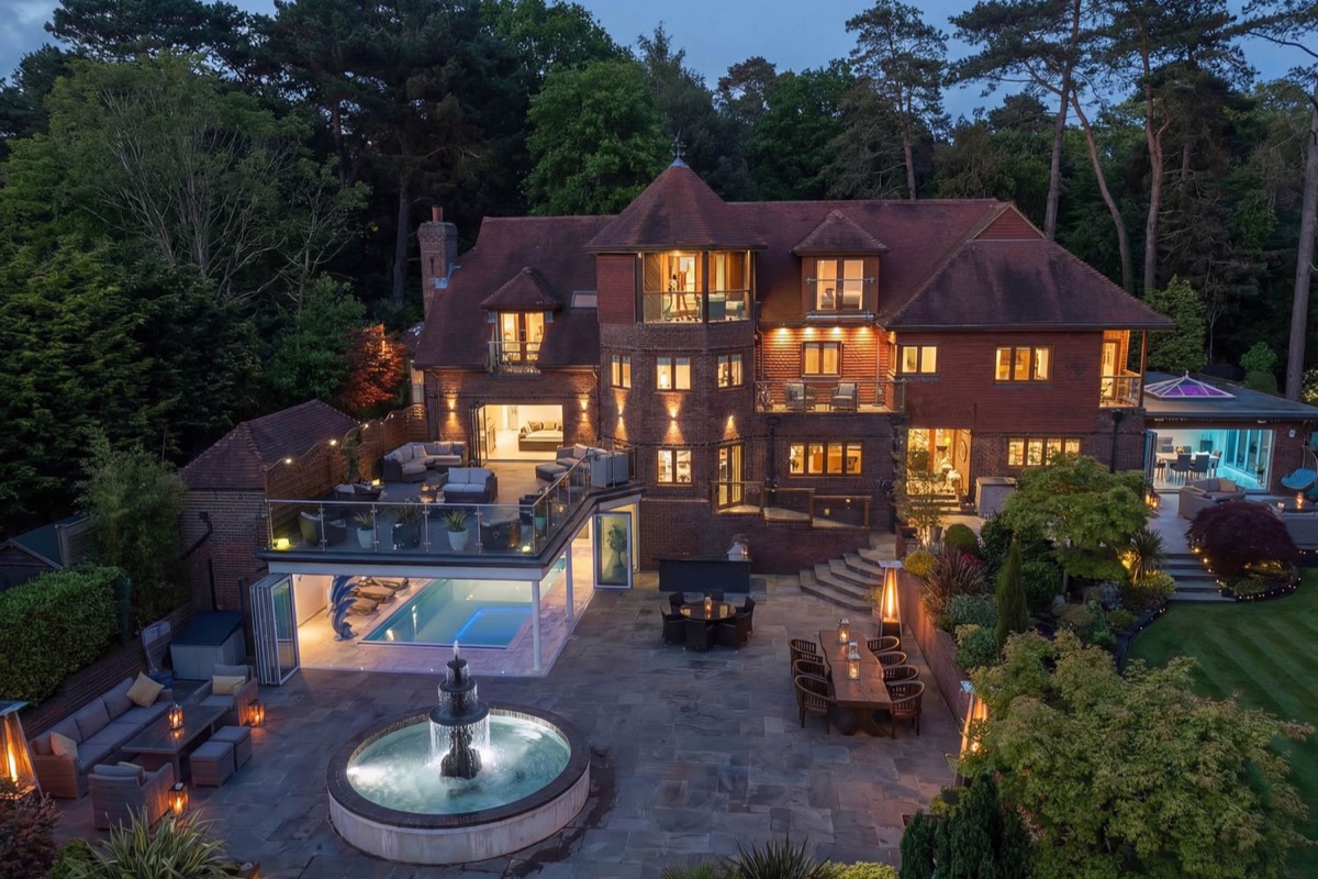 Hamble House at dusk with lit terraces, fountain and pool room