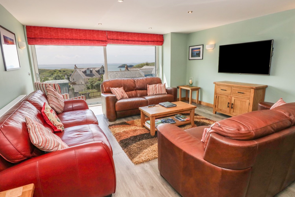 Living room with a wall of glass over Solva harbour and the sea at Harmon Vale