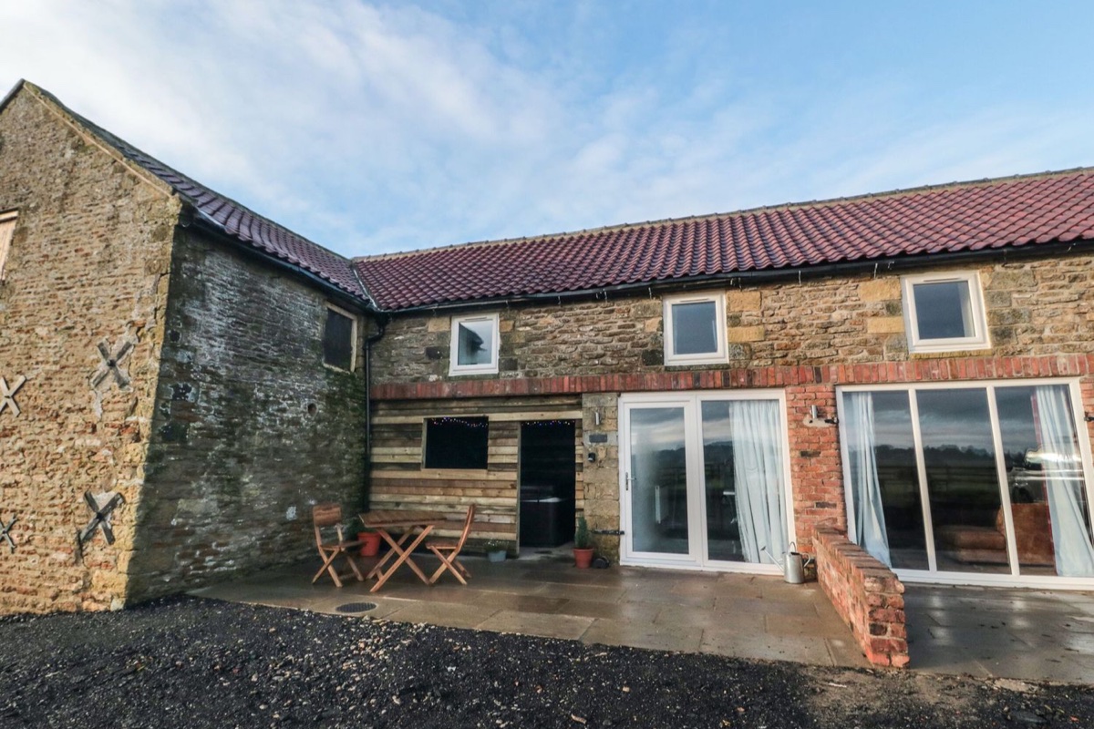 Hawthorn Cottage stone exterior with patio doors and outdoor table