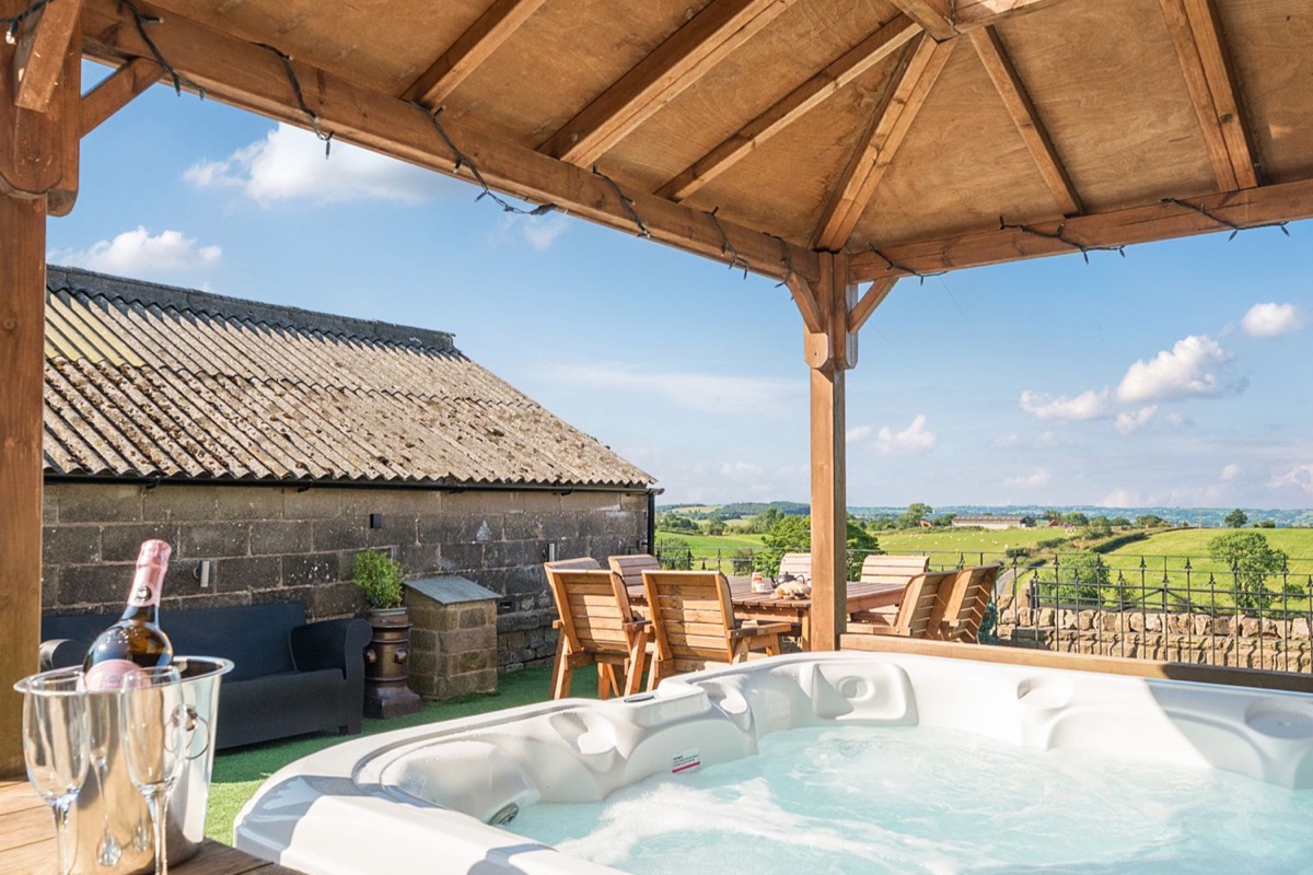 Hot tub under a timber pergola with open countryside views at HollyDale near Leek