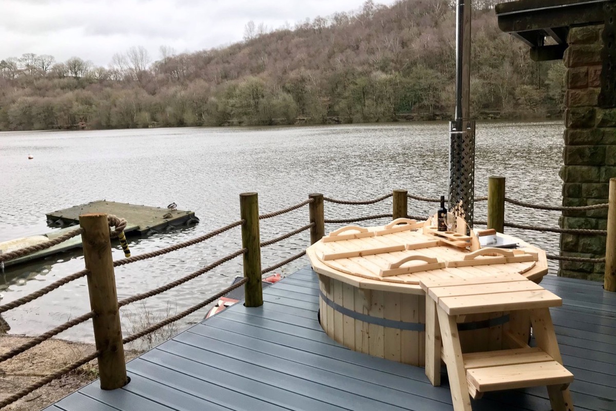 Wood-fired hot tub on a decked terrace beside the lake with a jetty at Horton Lodge Boathouse