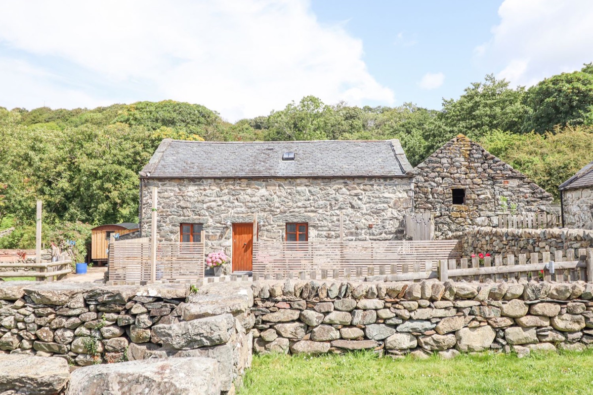 Isallt stone cottage exterior with garden wall and greenery