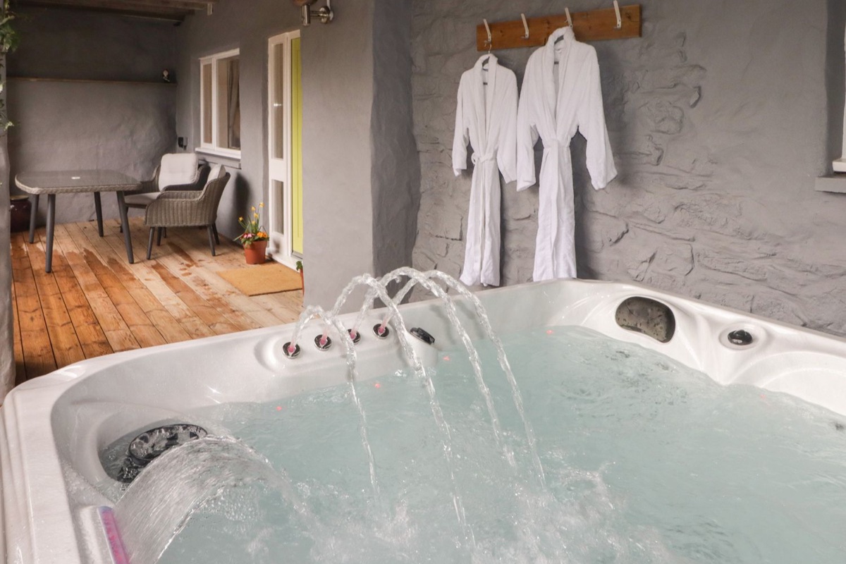 Covered hot tub with cascading jets and spa robes at Le Durkestrete Cellar
