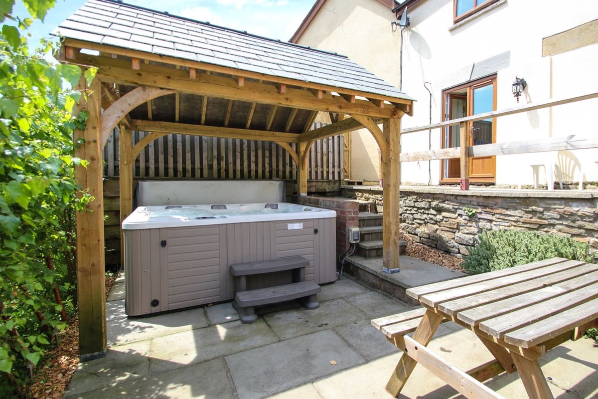 Covered hot tub beside the stone wall at Lilly Cottage