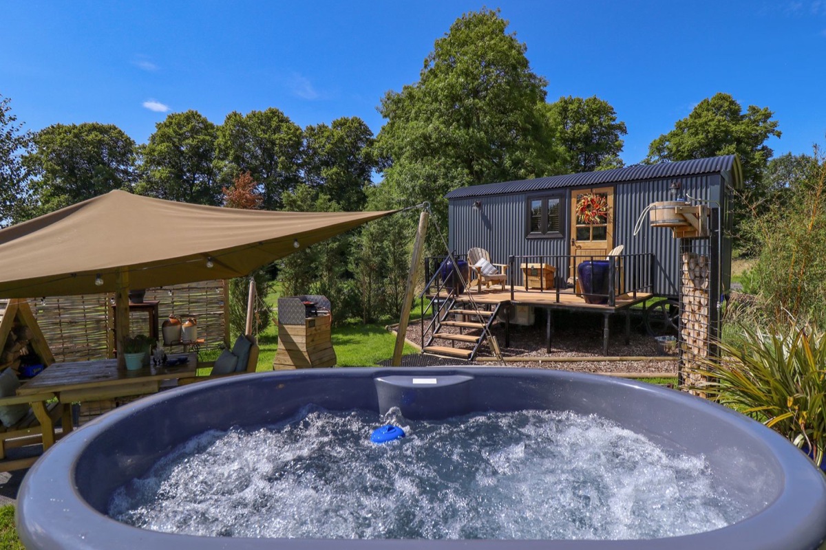 Portland hut hot tub in the foreground with the glamping hut beyond