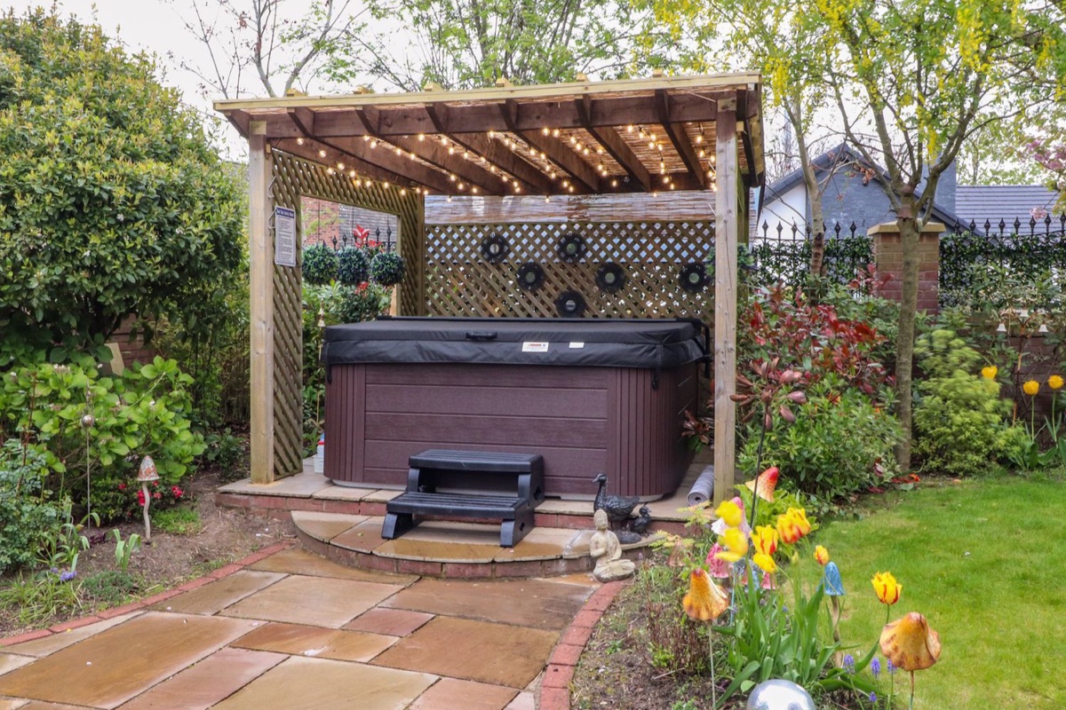 Linwood garden with covered hot tub, flowers and lawn