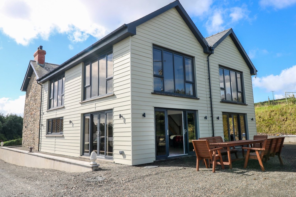 Two-storey Little Pale house with outdoor dining table under blue sky