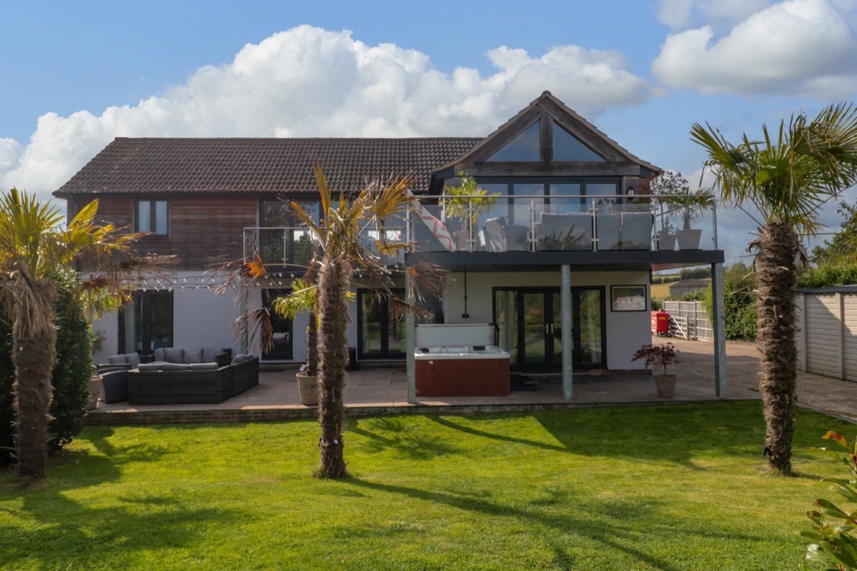 Longmynd exterior with garden seating, lawn and hot tub