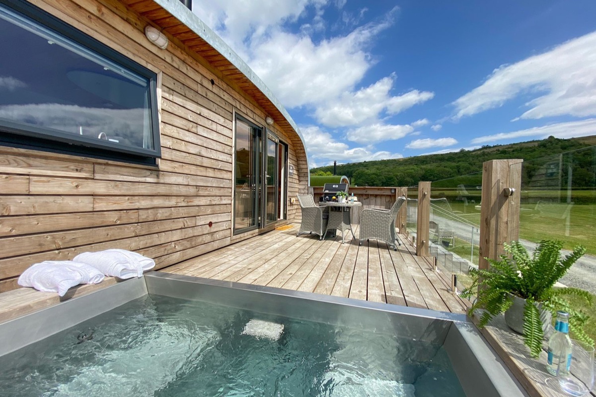 Glamping pod timber deck with a hot tub and wide countryside views at Low Longlands