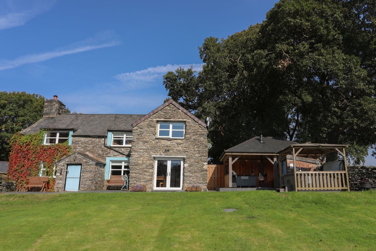 Maes Madog stone cottage exterior with lawn and covered hot tub area
