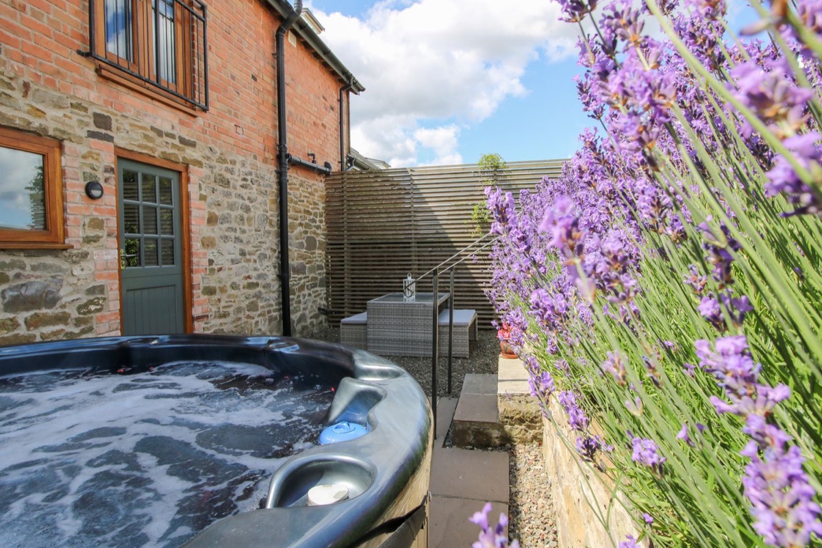 Meadow Barn hot tub beside lavender and the stone barn wall
