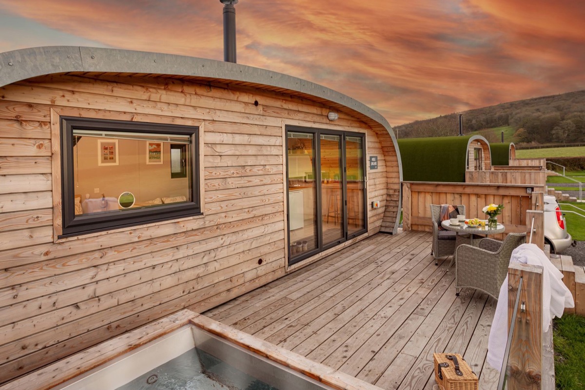 Cedar glamping pod with hot tub and timber deck bathed in sunset light near Cartmel