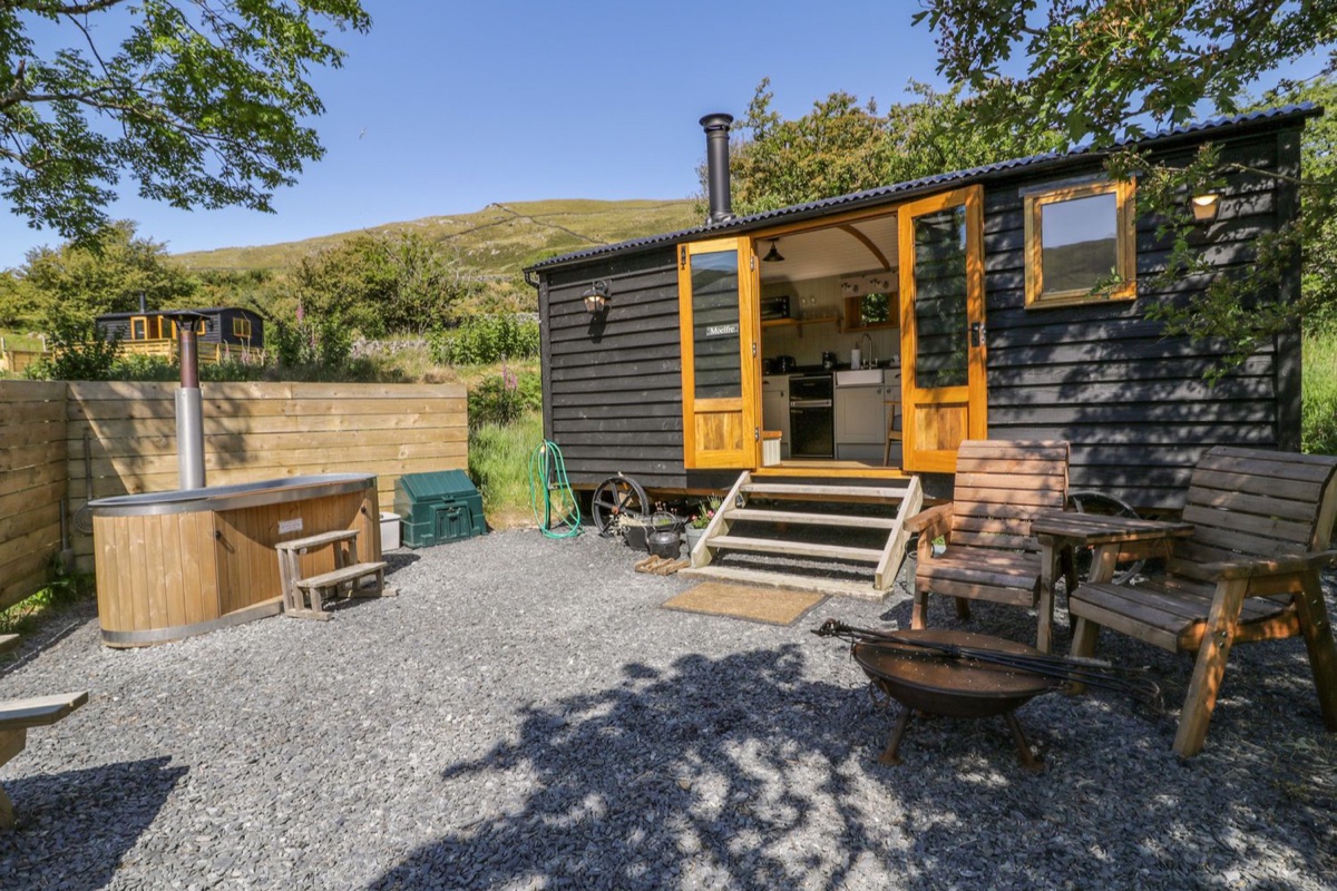 Moelfre Shepherds Hut exterior with hot tub and hillside setting