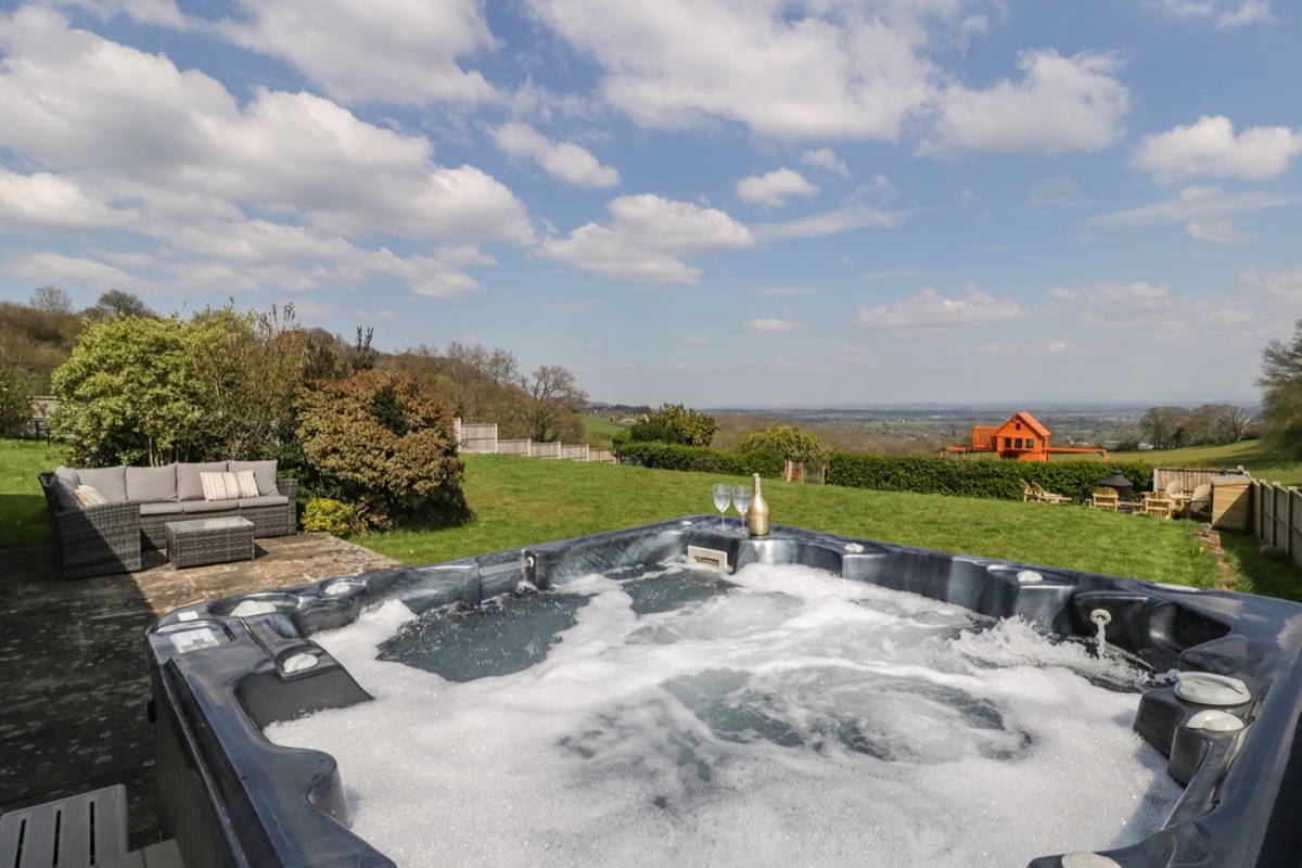 Hot tub and seating area with a wide countryside view at Moors Farm