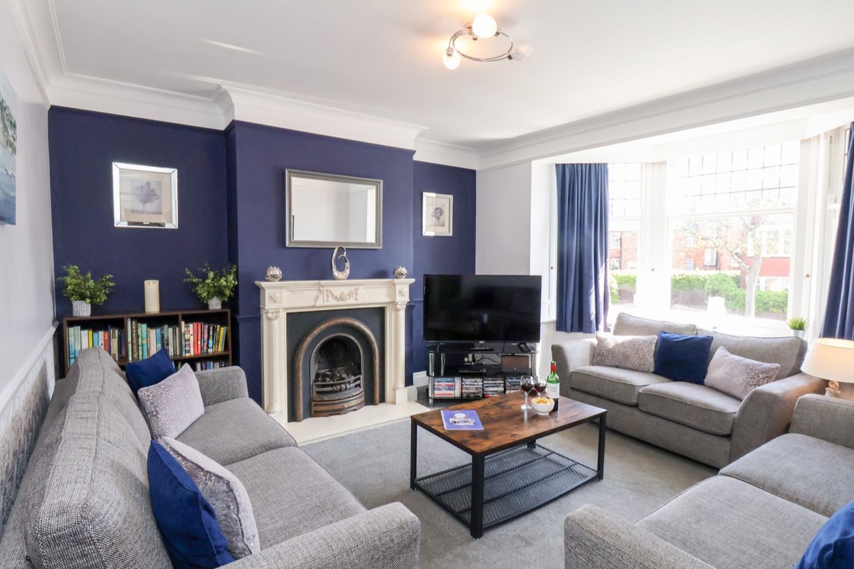 North Beach Lodge lounge with grey sofas, blue feature wall and bay window