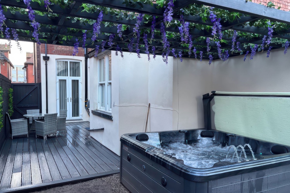 Orchard Lodge hot tub beneath a pergola beside rear doors