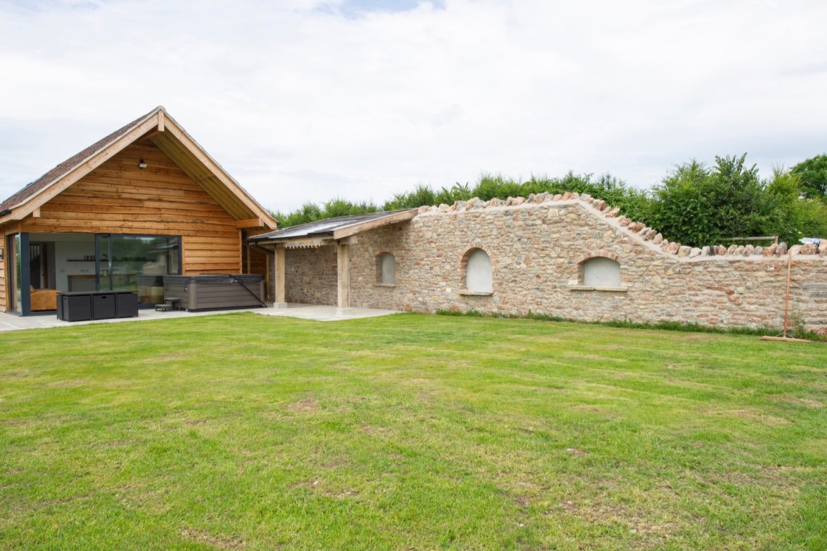 Owl Lodge lawn with stone wall and glass-fronted lodge