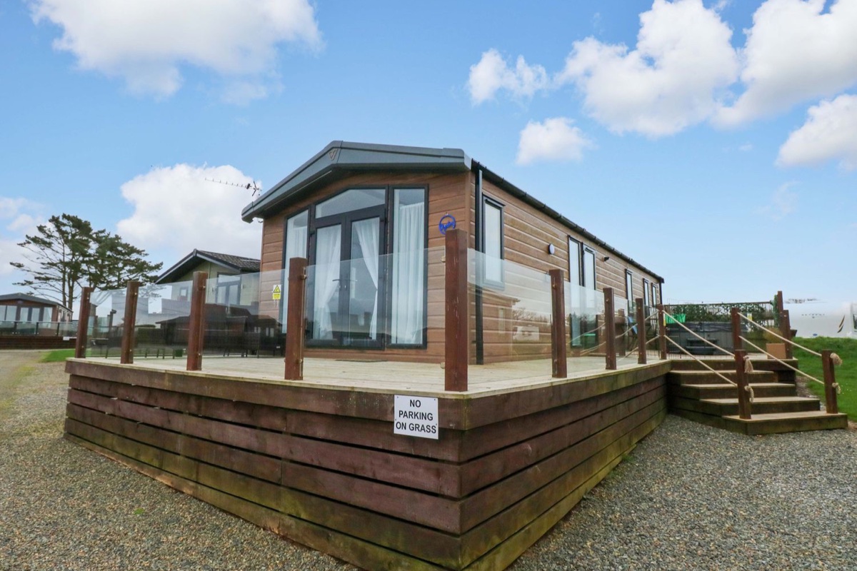 Oyster Lodge timber lodge on a raised deck under blue sky in Little Haven