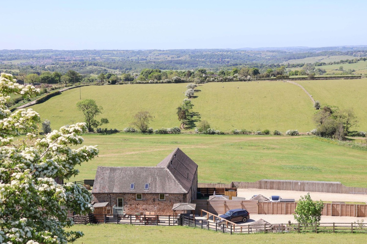 Stone barn set in rolling Moorlands countryside with fields and hawthorn blossom at Parlour Barn