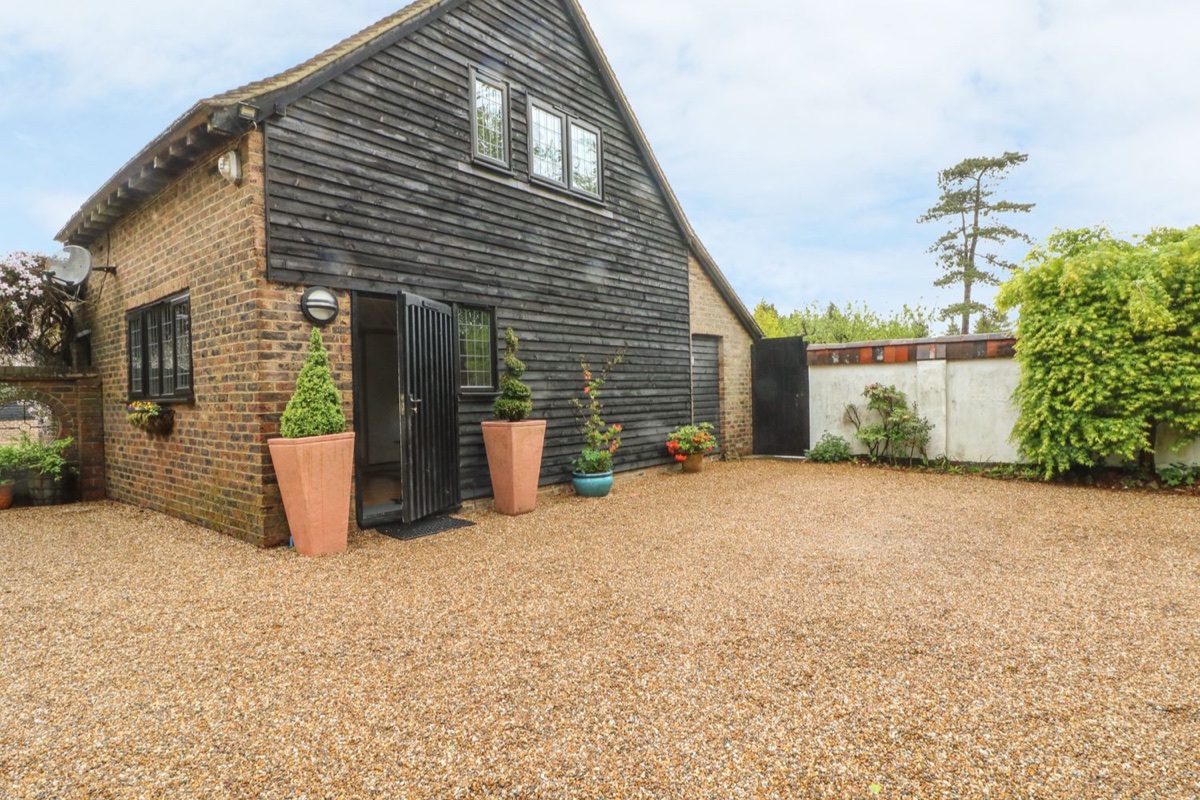 Pump House, a brick and black-weatherboard barn conversion with topiary and a gravel courtyard