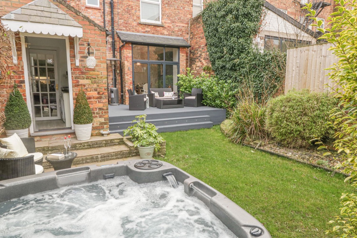 Royal Victoria House garden hot tub with brick house and deck beyond