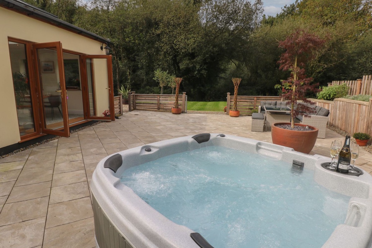 Hot tub on the patio beside bi-fold doors at Rudbaxton Water