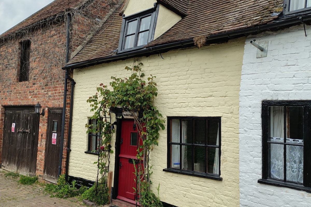 Runnymede cottage exterior with red front door and garden