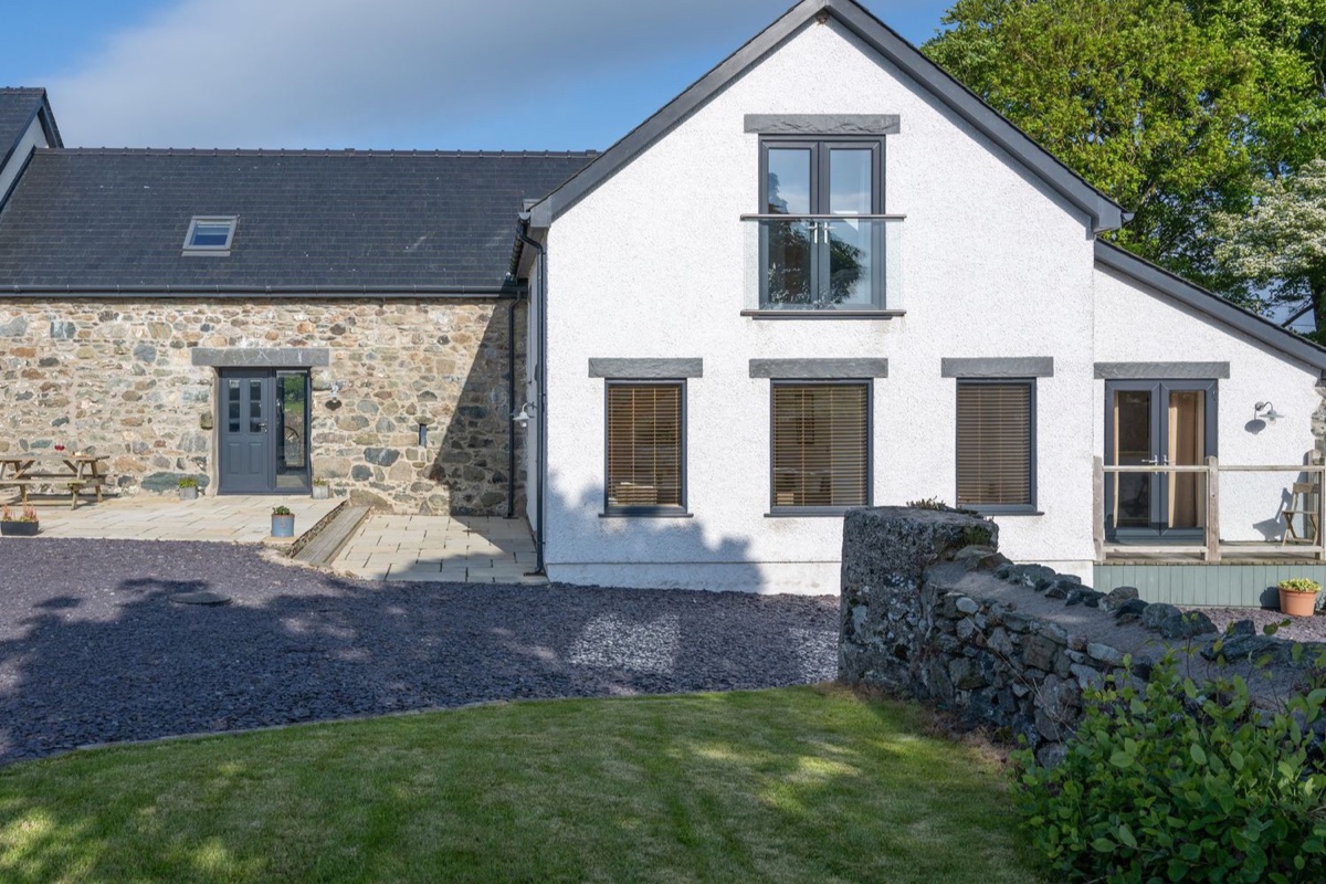 Sgubor cottage exterior with lawn and stone wall